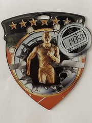 Male Track medal, shield shape 3″ x 2.5″ diameter, with ribbon, & engraving